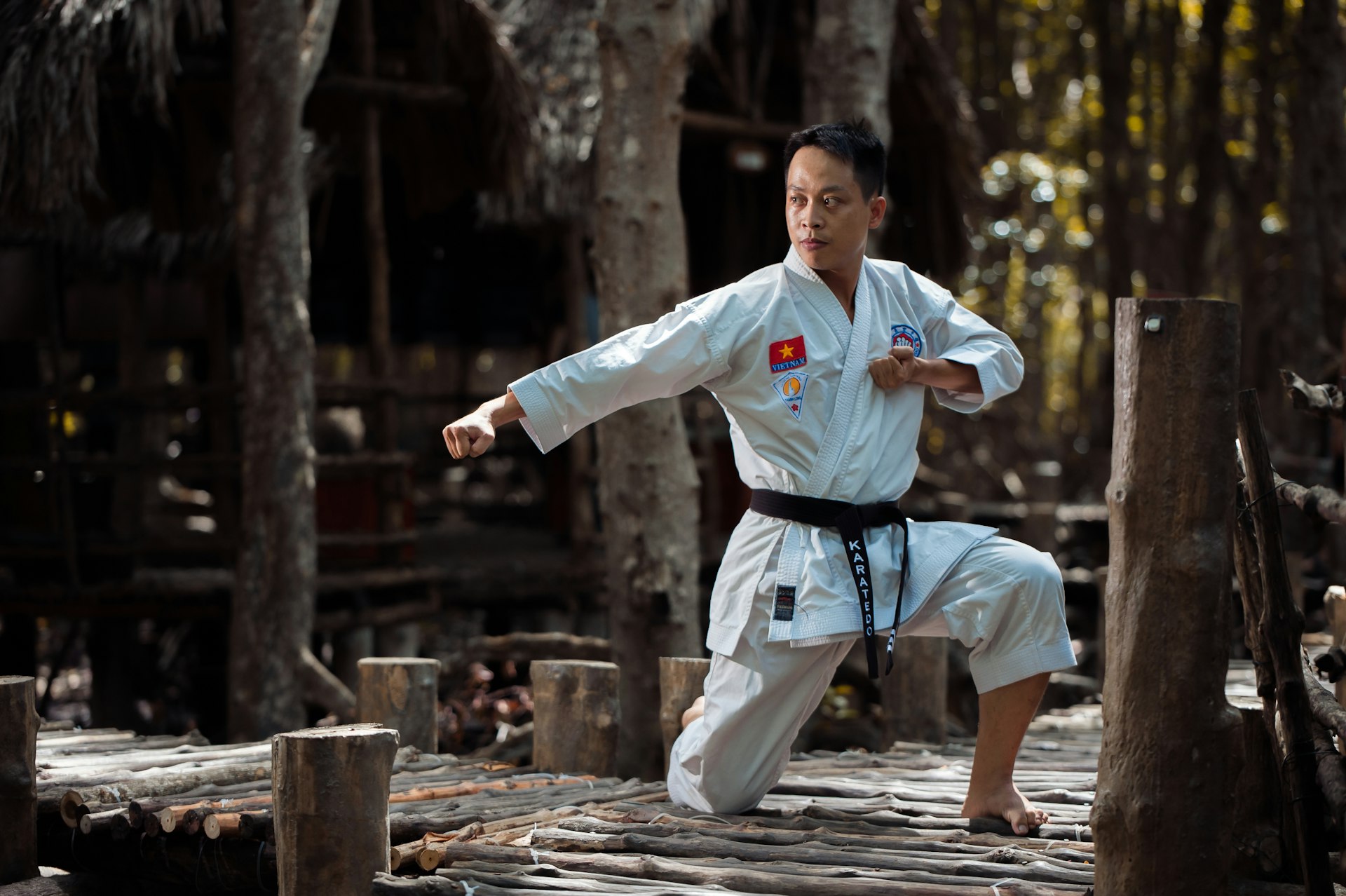 person wearing black belt karate gi training on wooden bridge